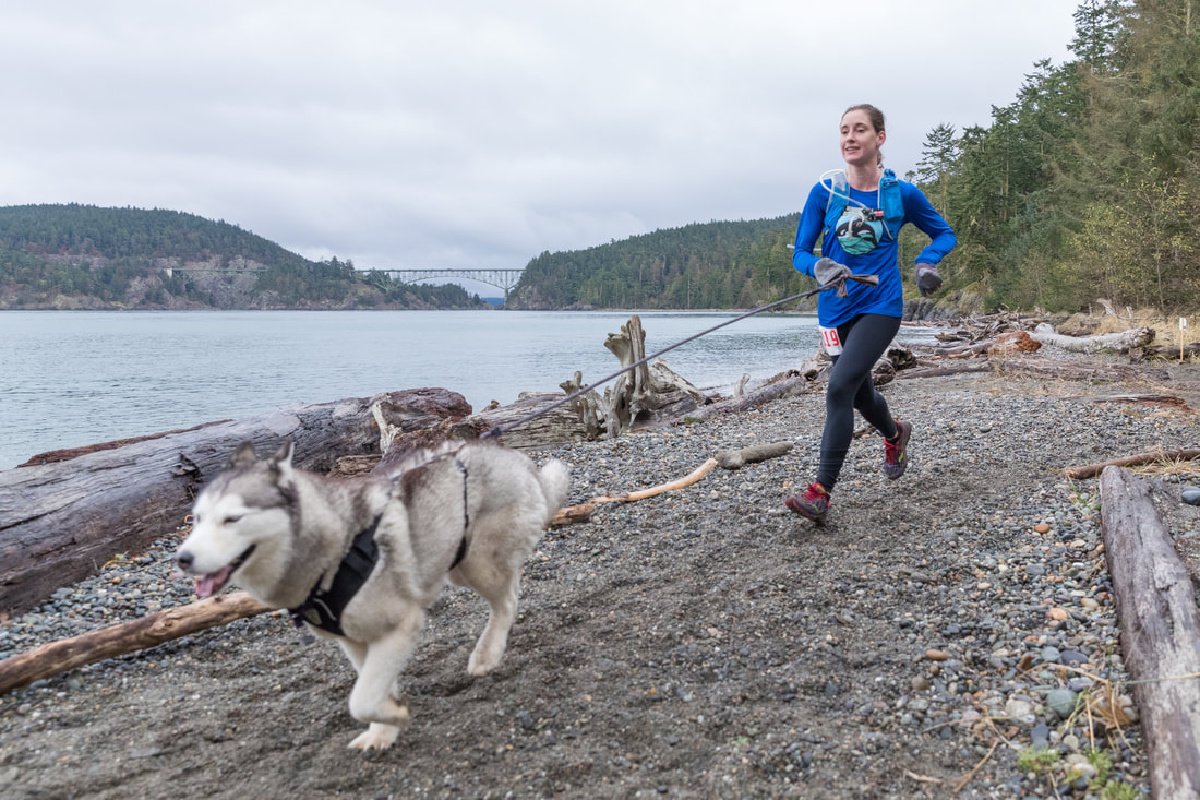 woman and husky running on the deception pass coastline